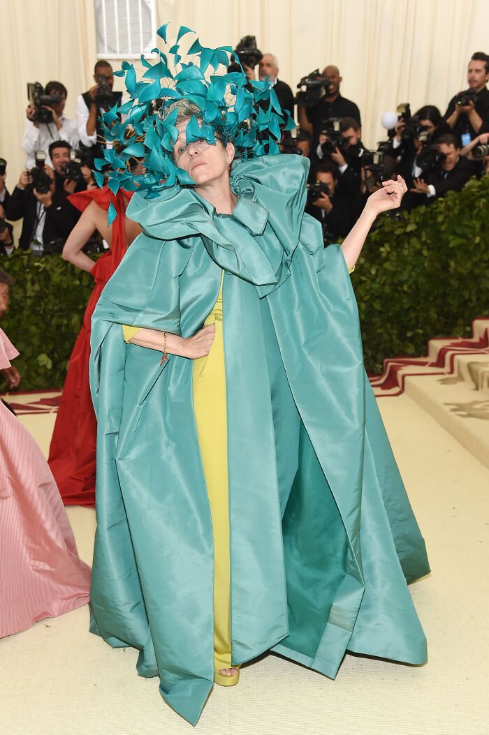 Celebrity in an elaborate teal and yellow outfit posing at the Met Gala, showcasing a bold fashion attempt.