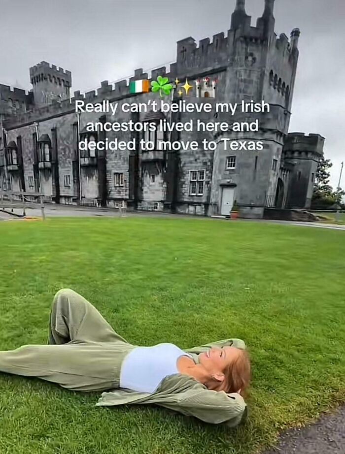 Woman lying on grass in front of a historic castle reflecting on American ignorance about Irish ancestors and locations.