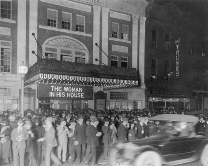 Crowd gathered outside a theater in America from 100 years ago, showcasing life in historic American cities.