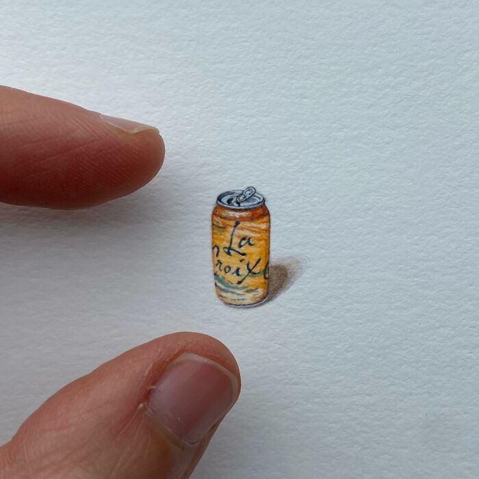 Tiny one-inch painting of an orange La Croix can held between fingers by artist Brooke Rothshank.