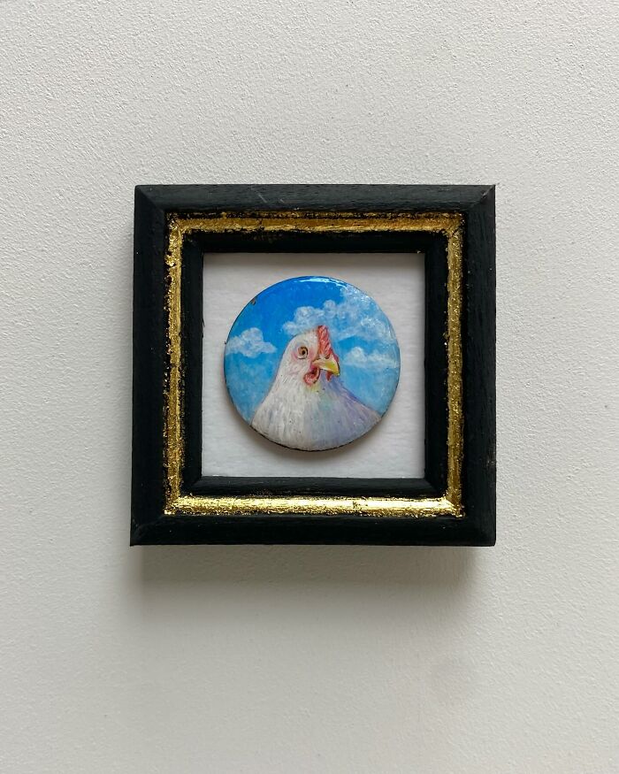 Tiny one-inch painting of a chicken on a circular canvas with a blue sky background in a black and gold frame.