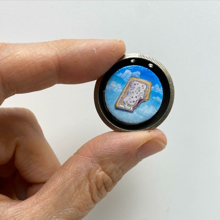 Hand holding one-inch tiny painting of a frosted pop tart against a blue sky background by Brooke Rothshank.