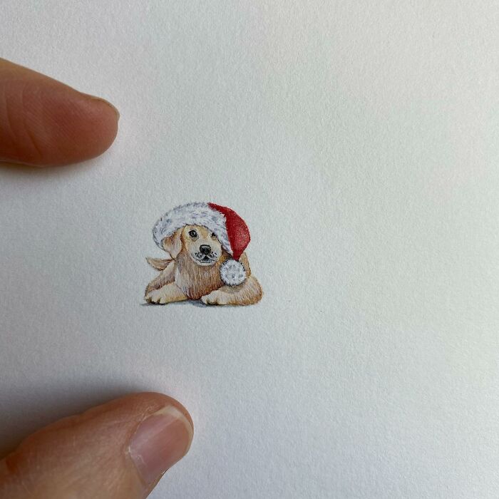 Tiny one-inch painting of a puppy wearing a Santa hat, showcasing detailed everyday art by Brooke Rothshank.