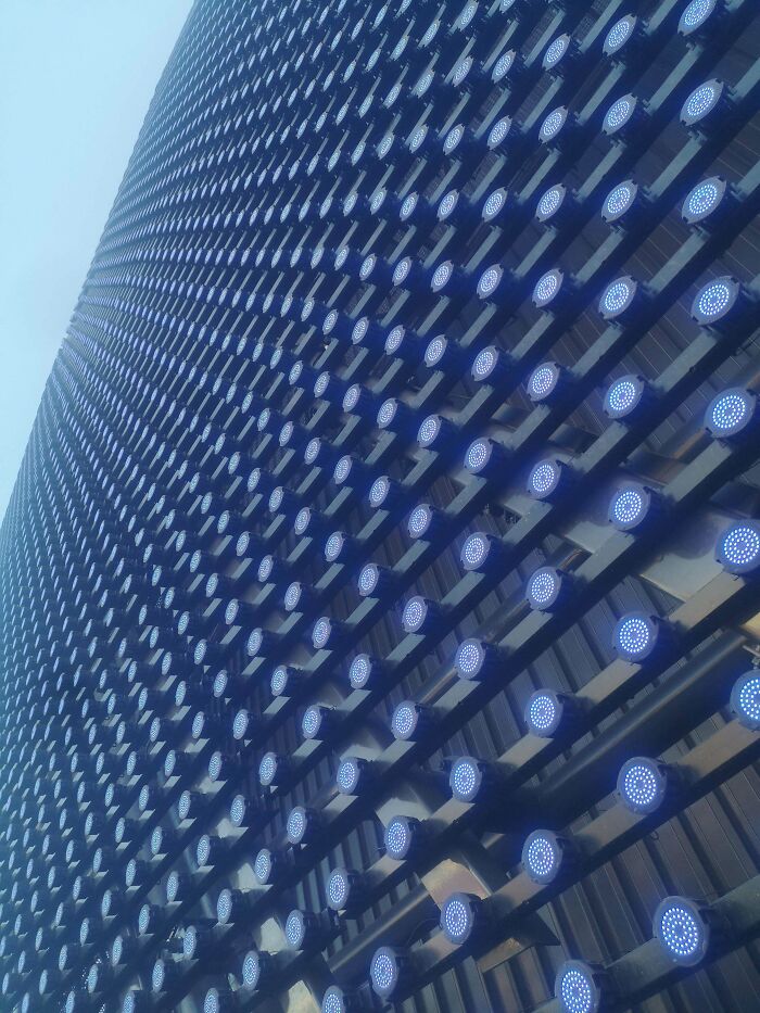 Abstract view of a building facade featuring rows of circular lights, an alternate angle revealing unique architectural details.