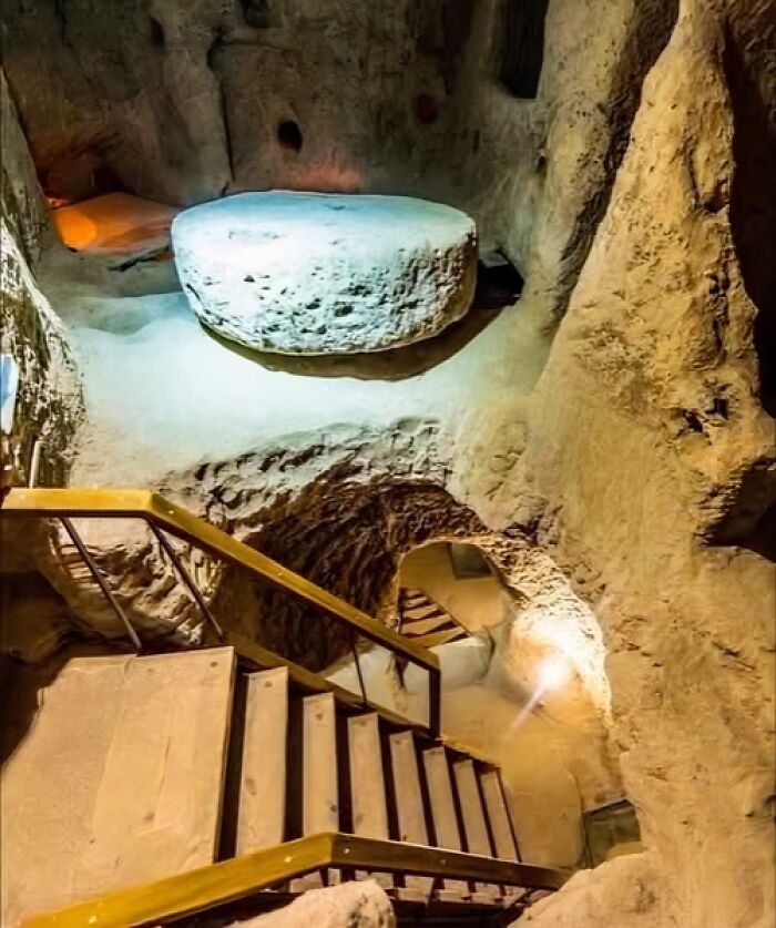 Ancient underground passage with stone walls, stairs, and carved circular stone table from archaeology news and architecture.