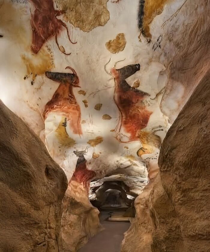 Prehistoric cave paintings of animals on a rock ceiling inside an ancient archaeology site.