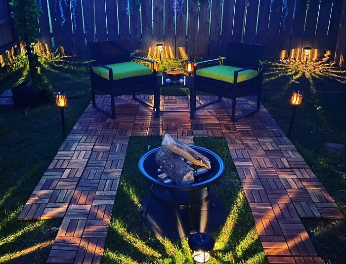 Cozy backyard outdoor upgrades with fire pit, wooden tile flooring, ambient lighting, and comfortable seating for summer gatherings.