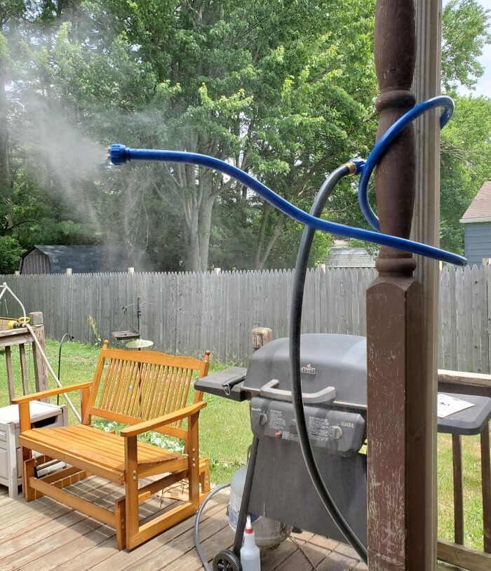 Backyard with outdoor upgrades including a misting system near grill and wooden bench enhancing summer comfort.