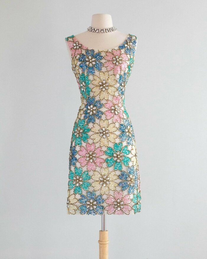 Floral beaded dress on mannequin showcasing centuries of fashion with vibrant pastel colors and intricate detailing.