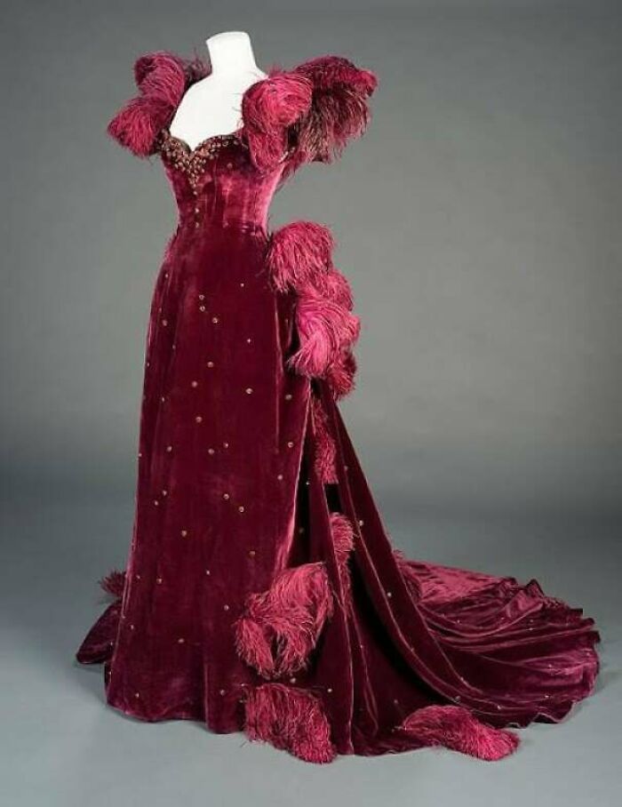 Velvet vintage gown with feather details and embellishments, showcasing centuries of fashion history in a dramatic style.