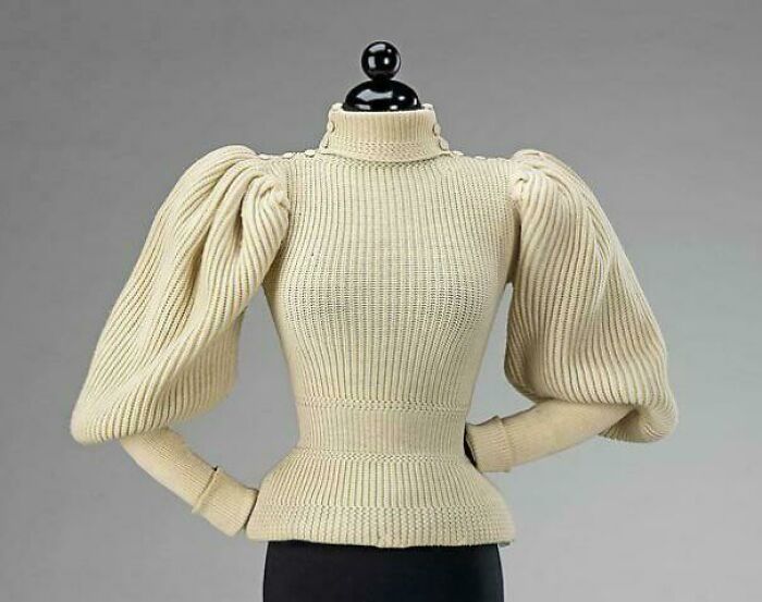 Beige vintage knitted sweater with exaggerated puff sleeves displayed on a mannequin for fashion centuries showcase.