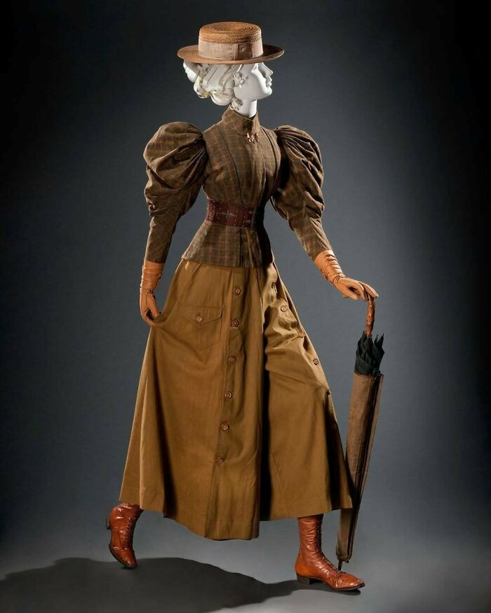 Vintage fashion outfit with puffed sleeves, wide belt, straw hat, and umbrella showcasing centuries of fashion history.