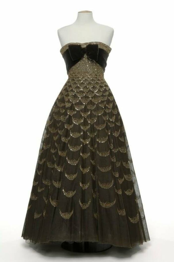 Strapless vintage gown with black bow and gold scalloped sequin detailing showcasing centuries of fashion history.