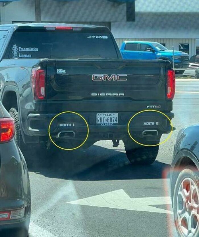Black GMC Sierra truck with exhaust pipes labeled HDMI 1 and HDMI 2, a blursed image that may confuse viewers.