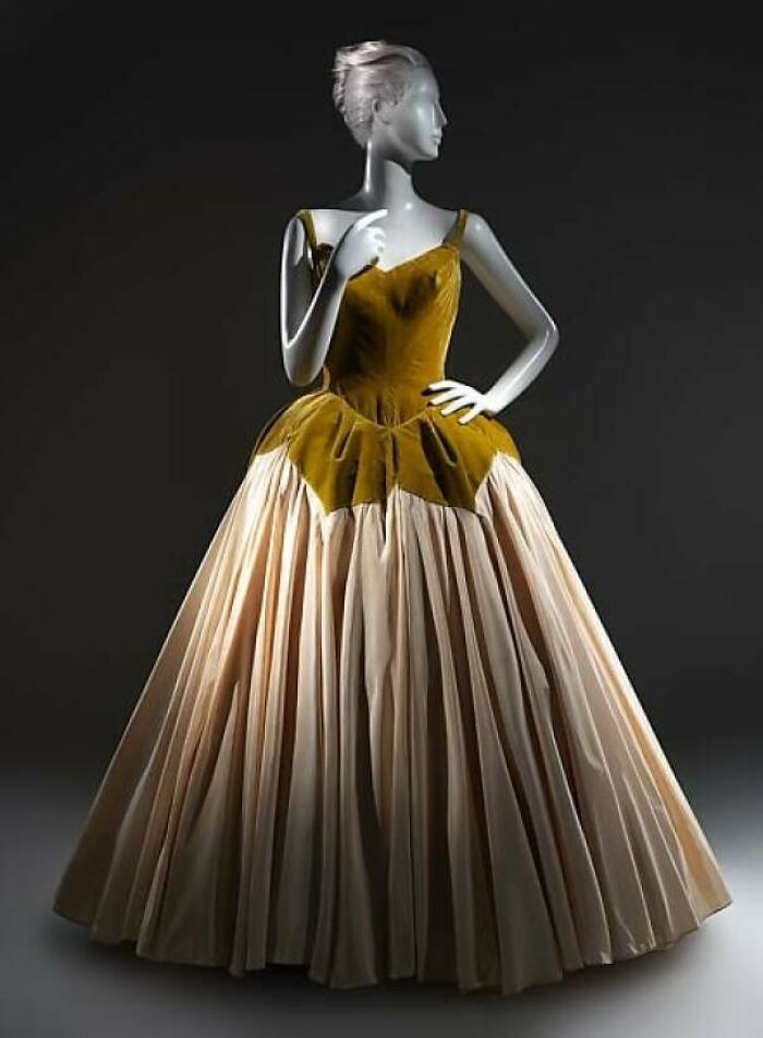 Vintage gown with a mustard velvet bodice and cream full skirt displayed on a mannequin showcasing centuries of fashion.