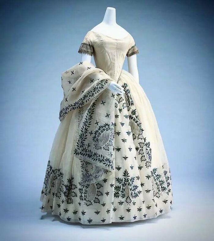 Vintage dress on mannequin with detailed embroidery showcasing centuries of fashion history and design evolution.