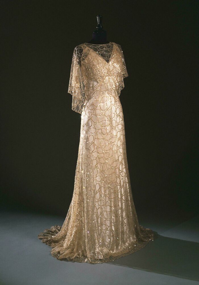 Elegant vintage gold lace gown displayed on a mannequin, showcasing centuries of fashion in a timeless design.