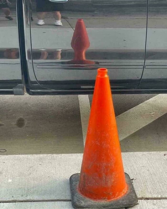 Orange traffic cone perfectly reflected in a car door, creating a blursed image that may make your brain short-circuit.