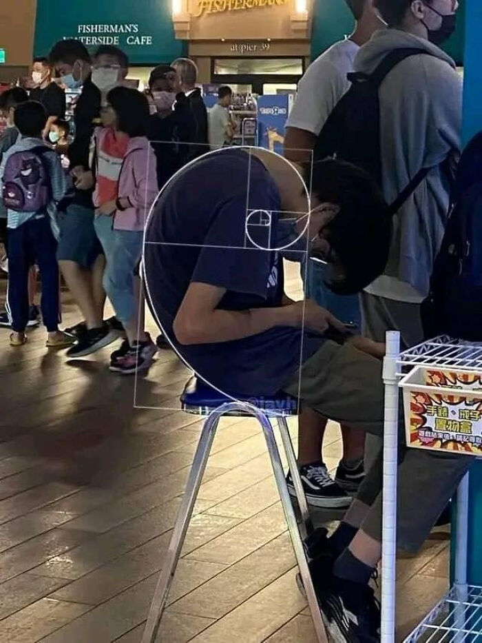Person sitting with back curved in a crowded area, with a golden spiral overlay illustrating unusual posture in blursed images.
