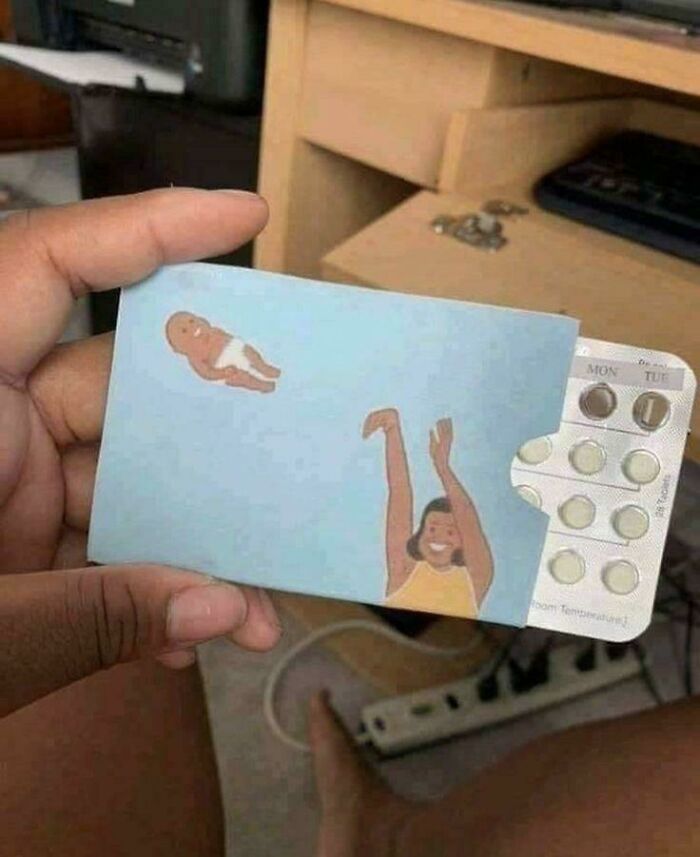 Hand holding a blister pack with playful artwork showing a woman tossing a baby, a blursed image that may confuse the brain.