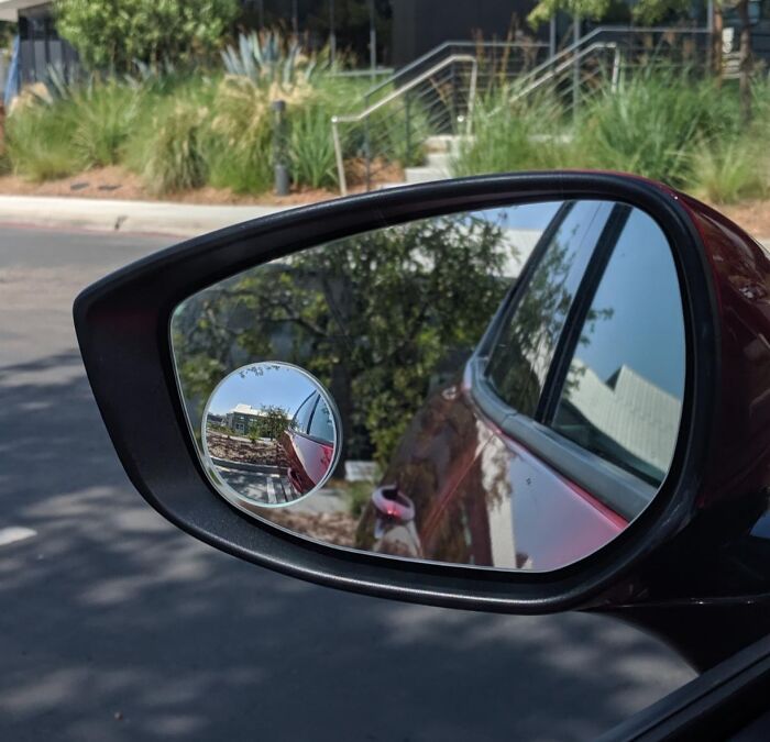 Car side mirror with clear view of a parking lot and greenery, showcasing useful adulting finds for practical living.