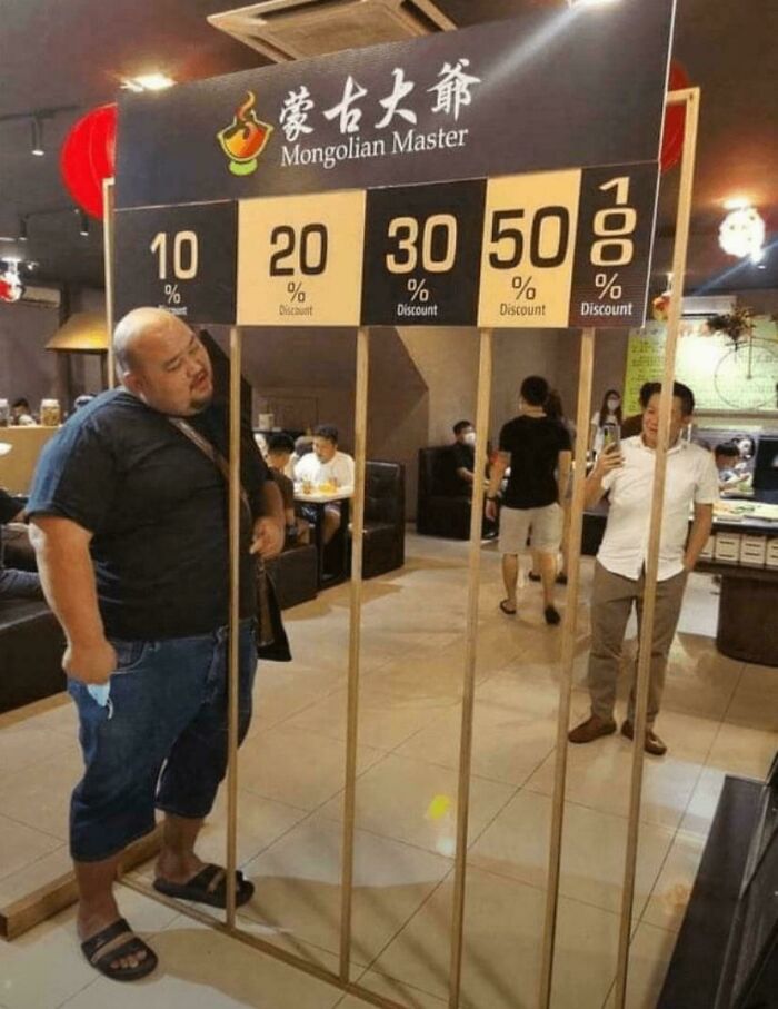 Man standing next to a discount frame causing a blursed visual effect in a restaurant setting.