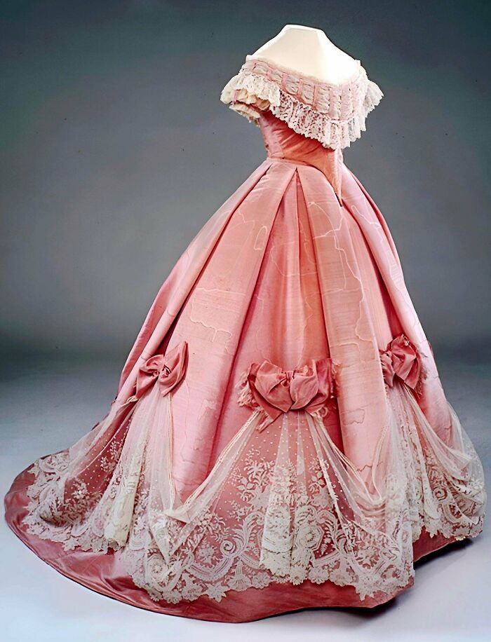 Victorian era pink ball gown with lace and bows showcasing centuries of fashion history and vintage design.