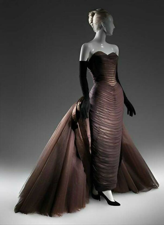 Elegant vintage gown with ruched design and long flowing train, showcasing centuries of fashion on a mannequin.