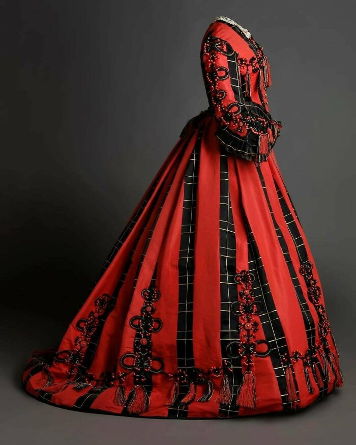 Victorian-era fashion dress in red and black with intricate patterns showcasing a few centuries of fashion.