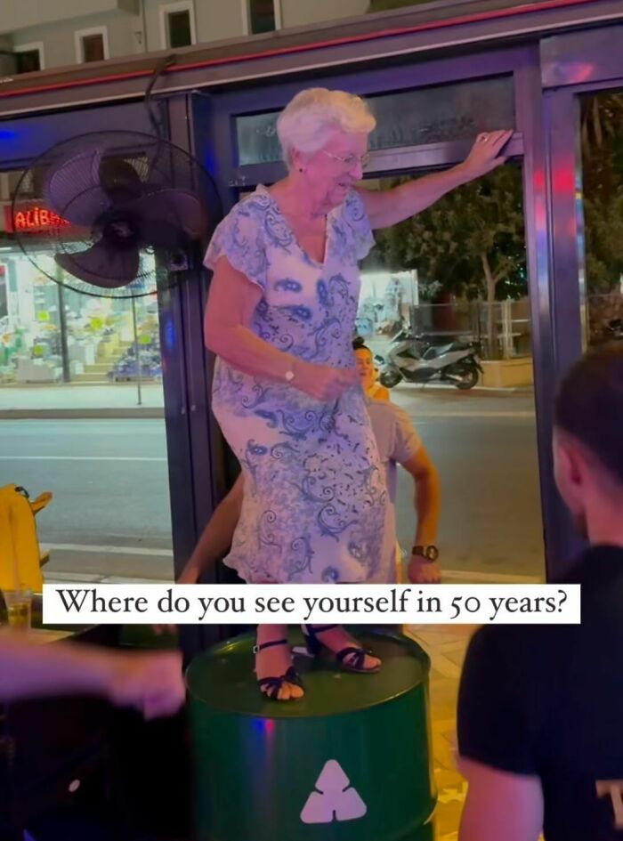 Elderly woman dancing on a barrel with sarcastic meme text about seeing yourself in 50 years, relatable humor moment.