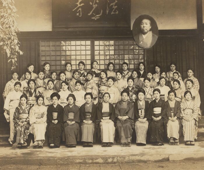 Group of Japanese women in traditional attire posing outside a wooden building, illustrating Japan in the 1800s.