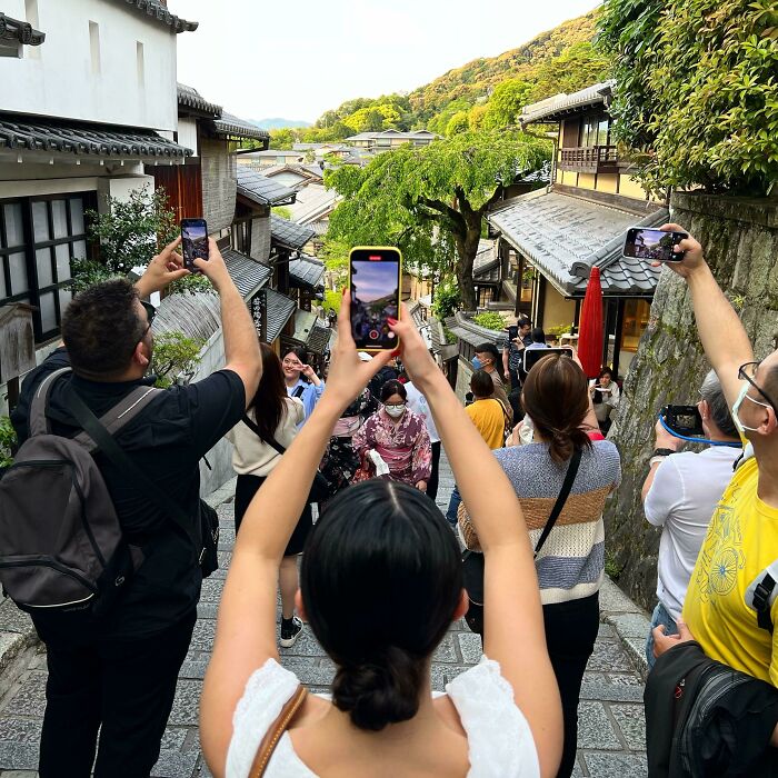 Tourists taking photos on a crowded street in a historic town, showcasing rude and obnoxious tourist behavior.