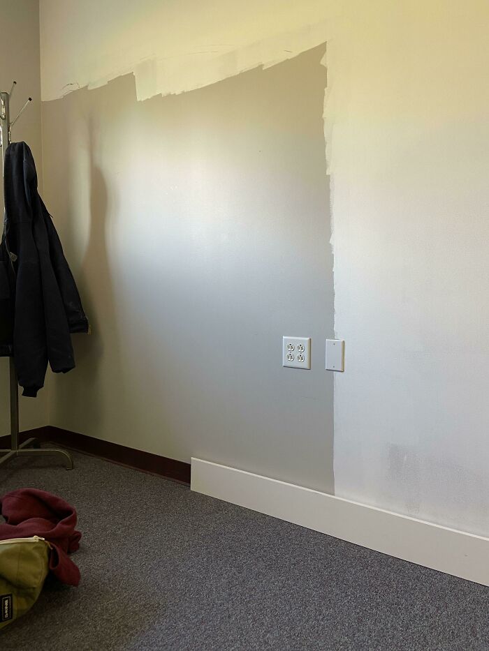Partially painted wall with uneven paint job and electrical outlets, showing infuriating landlord maintenance issues.