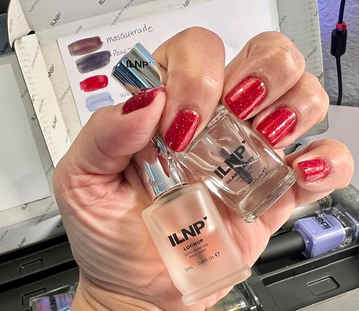 Hand holding ILNP nail polish bottles with red glitter nails, showcasing popular affordable finds on Amazon.