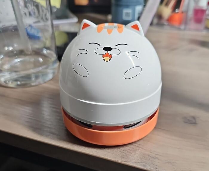 Small quirky cat-shaped desk gadget placed on a wooden surface, one of the weirdly wonderful finds collection.