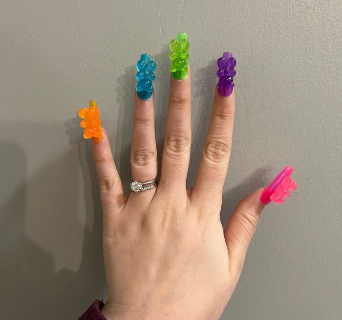 Hand with colorful gummy bear claw rings on each finger, showcasing weirdly wonderful finds and quirky accessories.
