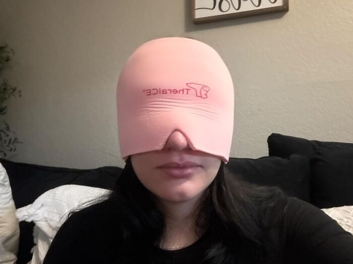 Woman wearing pink Therabace eye mask while relaxing on couch, an Amazon wishlist favorite stress relief product.