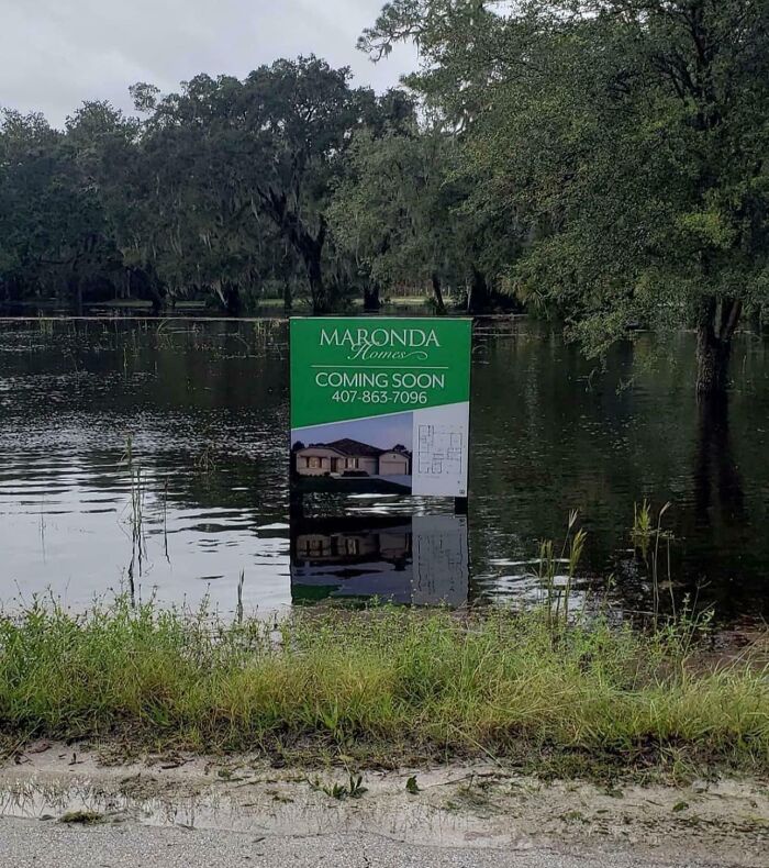 Flooded land with a Maronda Homes coming soon sign partially submerged, illustrating current life in the US.