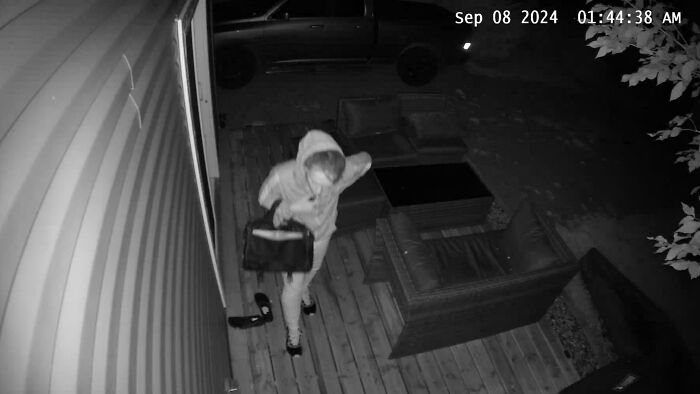 Person caught on security camera at night carrying a bag outside a house, creating a creepy scene.