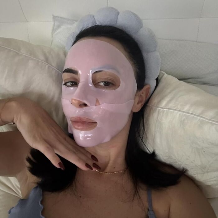 Woman relaxing with a pink face mask and headband as a Mother's Day splurge skincare gift for self-care.