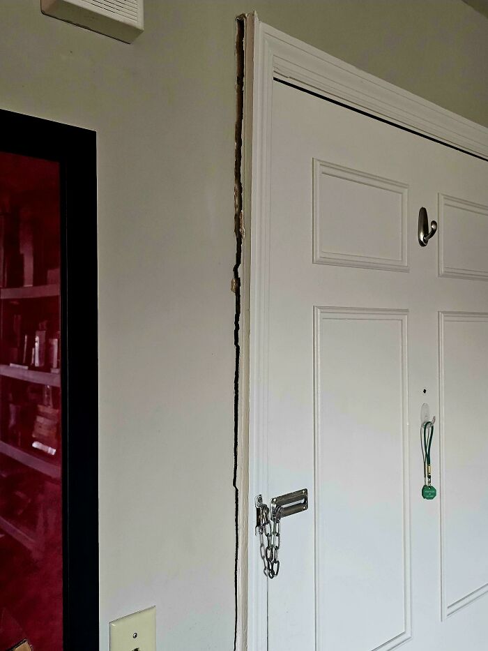 Door with insecure chain lock and damaged door frame, showing infuriating landlord neglect in rental property.