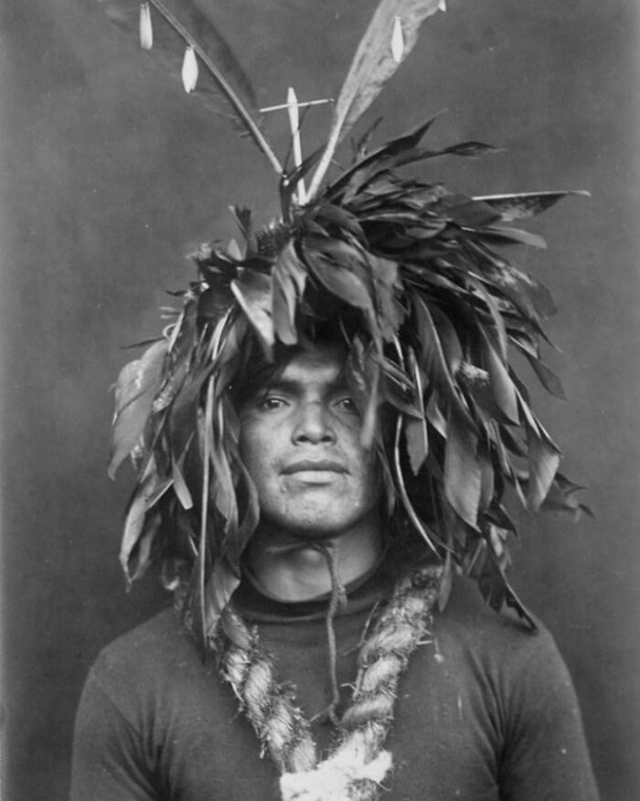 Native American man in traditional feathered headdress and necklace, early 1900s portrait revealing cultural heritage.