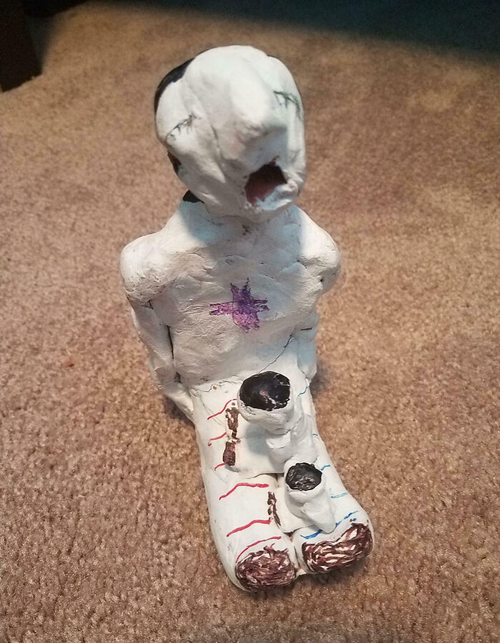 Creepy handmade clay figure with distorted face and stitched details, evoking unsettling and eerie feelings.