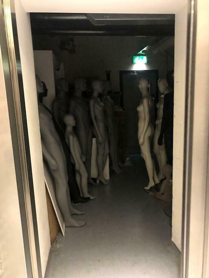 Dimly lit room filled with creepy mannequins standing closely together, creating an eerie atmosphere to share with others.