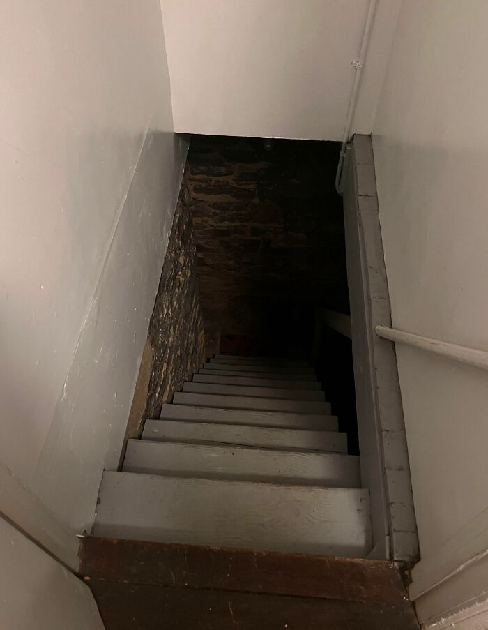 Narrow, dark basement stairs with stone walls creating a creepy atmosphere people had to share with others.