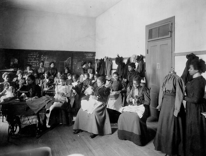 African American women sewing and learning in a classroom setting, showcasing African American life at the 1900 Paris Exposition.