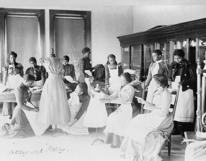 African American women sewing and fitting dresses in a classroom setting capturing African American life in 1900 Paris Exposition.