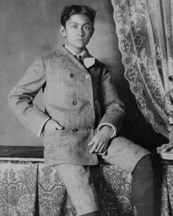 Young African American boy dressed in formal attire, posing in an elegant setting at the 1900 Paris Exposition.
