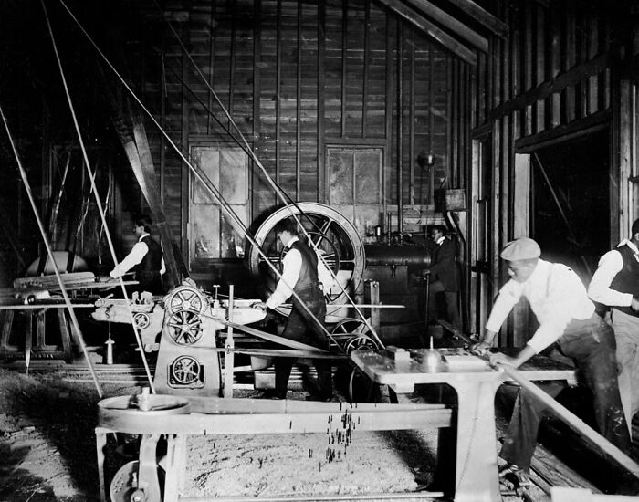 African American men working with industrial machinery in a 1900 Paris Exposition workshop capturing daily life.