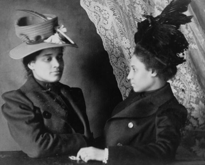 Two African American women in elegant hats and period clothing at the 1900 Paris Exposition, capturing African American life.